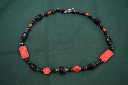A silver, onyx and carved coral necklace.