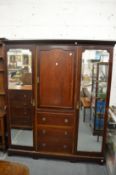 An Edwardian inlaid mahogany wardrobe with central door above three drawers flanked by mirrored full
