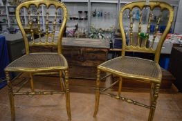 A pair of gilt wood spindle back and cane seated occasional chairs.