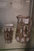 An opaque glass jug with matching beaker, both overlaid with engraved silver decoration.