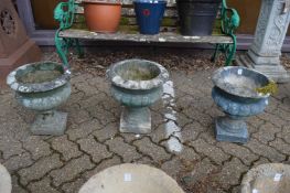 A set of three reconstituted stone pedestal planters.