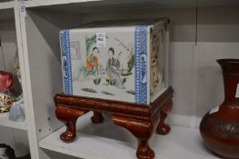 A Chinese famille rose porcelain pillow with later wooden stand.