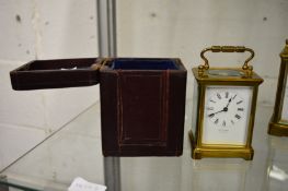 A brass carriage clock, the white enamel dial signed W Lockwood, complete with leather travelling