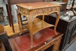 A carved walnut two-tier occasional table.