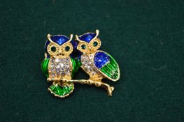 A gilt metal, enamel and diamante owl brooch.