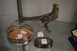A silver pill box, plated bottle coaster and a plated model of a pheasant.