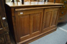 A walnut low two door cupboard with brushing slide.