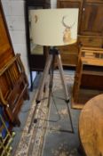 A tripod standard lamp with decorative shade.