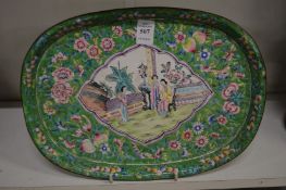 A Canton enamel oval tray painted with a panel depicting figures in a courtyard.