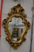 A small gilt plaster wall mirror.