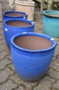 A set of three blue glazed terracotta planters.