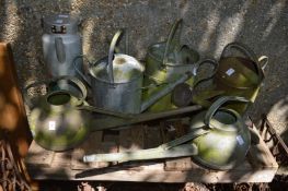 A quantity of galvanised watering cans.