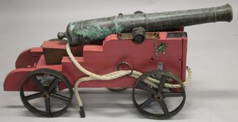 A MID 18TH CENTURY FRENCH BRONZE CANNON on a wooden stand with metal wheels. Cannon 99cm long.
