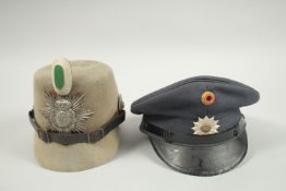 A WW I GERMAN JAGER SHAKO ALONG WITH A STATE OF LOWER SAXONY WEST GERMAN POLICE HAT.