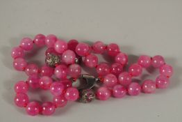 A STRING OF FIFTY PINK JADE AND DIAMOND BEADS. 60cms long.