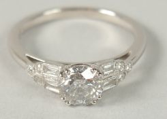 AN 18CT WHITE GOLD DIAMOND SOLITAIRE RING SET WITH RBC AND BAGUETTE CUT DIAMOND SHOULDERS, boxed.
