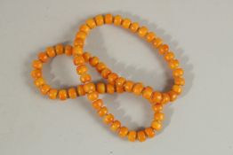 A STING OF SEVENTY AMBER BEADS.