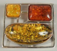 A SILVER AND THREE COLOURED AMBER BROOCH.