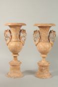 A PAIR OF PINK TWO HANDLED CLASSICAL POTTERY VASES. 44cm high.