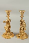 A GOOD PAIR OF GILT BRONZE CLASSICAL CANDLESTICKS as young men riding horses. 28cms high.