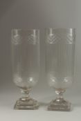 A GOOD PAIR OF GLASS STORM LANTERNS with reeded sides on square stepped bases. 40cm high