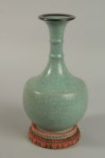 A CHINESE CELEDON CRACKLE GLAZE VASE with stand. 25cm high.