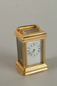 A MINIATURE BRASS CARRIAGE CLOCK with black and white dial and carrying handles. 7cms.