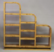 AN ART DECO DESIGN BLOND WOOD BOOKCASE OR ROOM DIVIDER of stepped form with an arrangement of ten