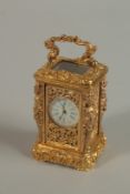 A MINIATURE BRASS ORNATE CARRIAGE CLOCK with finial mounts and carrying handles. 7cm high.