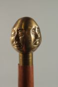 A WALKING STICK with brass four face handle. 92cm long.