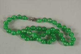 A STRING OF FORTY-FOUR GREEN JADE BEADS with diamond snake clasp.