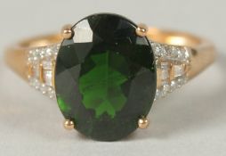 A 9CT YELLOW GOLD RING SET WITH OVAL GREEN DIOPSIDE AND DIAMOND SET SHOULDERS, boxed. diopside, 3.