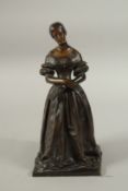 A GOOD 19TH CENTURY BRONZE OF A YOUNG LADY, hands crossed holding a book. 30cms high.