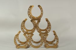 A METAL HORSESHOE WINE RACK FOR SIX BOTTLES. 40cms high.