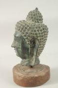 A LARGE THAI BRONZE BUDDHA HEAD, raised and mounted to a circular wooden base, head 31cm high,