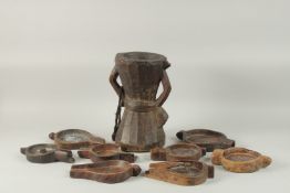 A LARGE 19TH CENTURY ARAB POSSIBLY OMANI CARVED WOODEN COFFEE MORTER, together with eight coffee