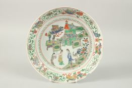 A CHINESE FAMILLE VERTE PORCELAIN DISH, painted with figures in a courtyard, mark to base, 25cm