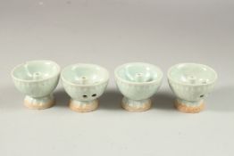 A COLLECTION OF FOUR PALE CELADON GLAZED POTTERY OIL LAMPS.