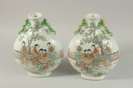 A PAIR OF CHINESE PORCELAIN TWIN HANDLE MOON FLASKS, painted with female figures and children in a