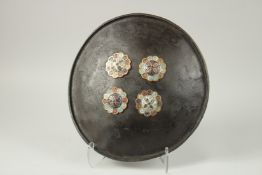 A 19TH CENTURY NORTH INDIAN LACQUERED HIDE SHIELD, with enamelled gilt metal bosses, 42cm wide.