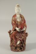 A LARGE CHINESE FLAMBE PART-GLAZED PORCELAIN GUANYIN, the figure depicted seated upon a rocky mound,