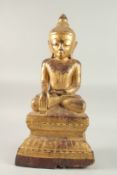 A LARGE BURMESE GILT LACQUERED CARVED WOODEN BUDDHA, with a band of inscription to the base, 60cm