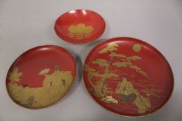 THREE JAPANESE GILT AND RED LACQUER SAKE DISHES, two depicting scenes of figures - both signed,