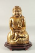 A LARGE GILDED CARVED WOODEN BUDDHA WITH OVAL HARDWOOD STAND, Buddha 52cm high, base 29cm wide,