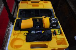 A laser level with tripod stand and a case of related equipment.