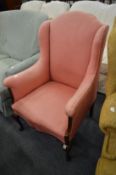 A small pink upholstered wing armchair with inlaid mahogany frame.
