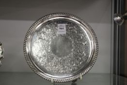 A Georgian circular salver with engraved decoration, gadroon edge on three cast feet.