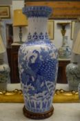 A large Chinese blue and white vase decorated with peacocks on a hardwood stand.