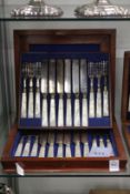 A mahogany cased set of mother of pearl handled dessert knives and forks.