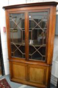 A large mahogany standing corner display cabinet.